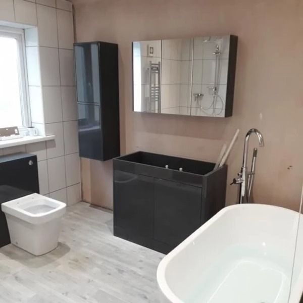 Refitted bathroom with a freestanding bath, dark vanity units and a mirrored cabinet